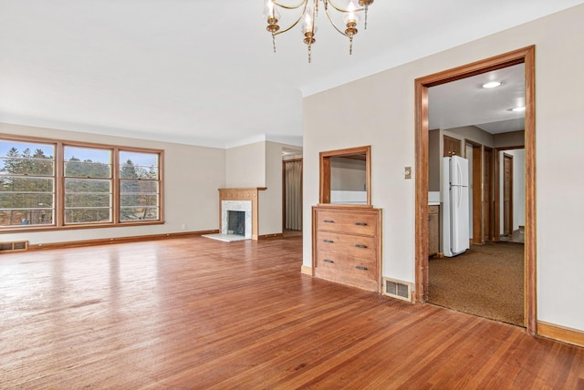 unfurnished living room with wood-type flooring and a notable chandelier