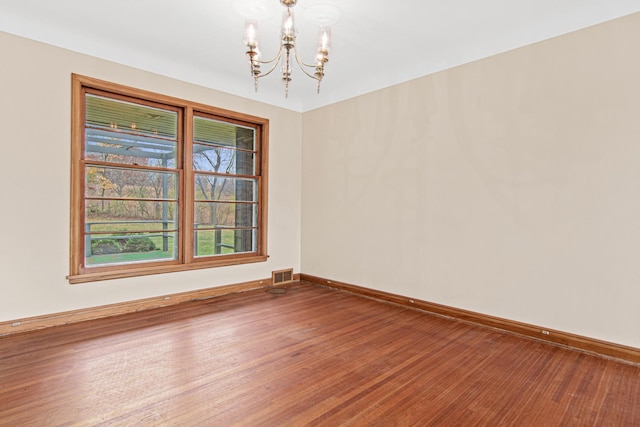 spare room with a notable chandelier and hardwood / wood-style flooring