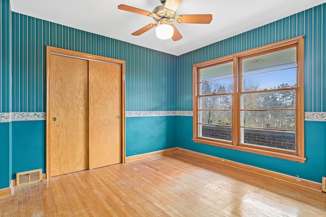 unfurnished bedroom with wood-type flooring, a closet, and ceiling fan