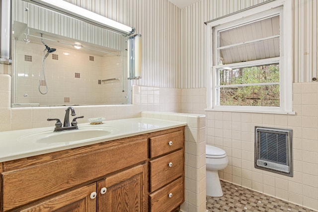 bathroom featuring heating unit, vanity, tile walls, and toilet