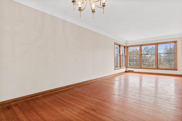 spare room featuring a notable chandelier and hardwood / wood-style flooring