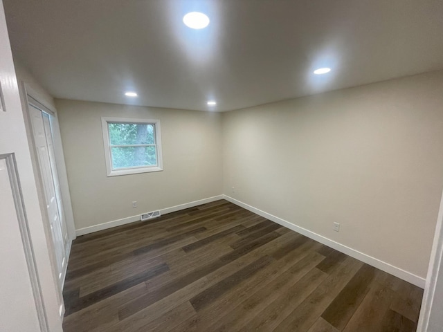 unfurnished room featuring visible vents, dark wood finished floors, and baseboards