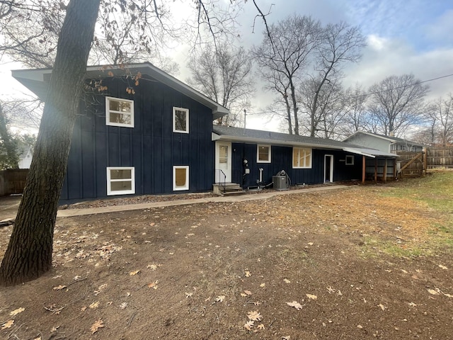 view of front of house with central AC unit, fence, and board and batten siding