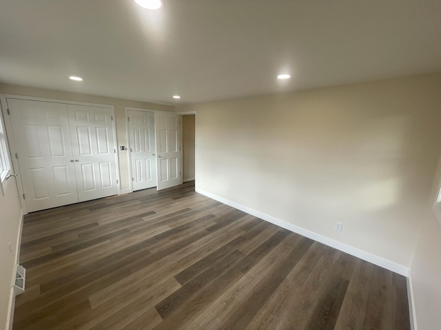 unfurnished bedroom with dark wood-style floors, recessed lighting, two closets, and baseboards