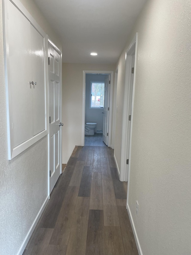 hall featuring dark wood-type flooring and baseboards