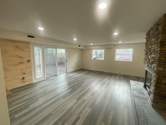 unfurnished living room featuring recessed lighting, baseboards, wood finished floors, and a stone fireplace