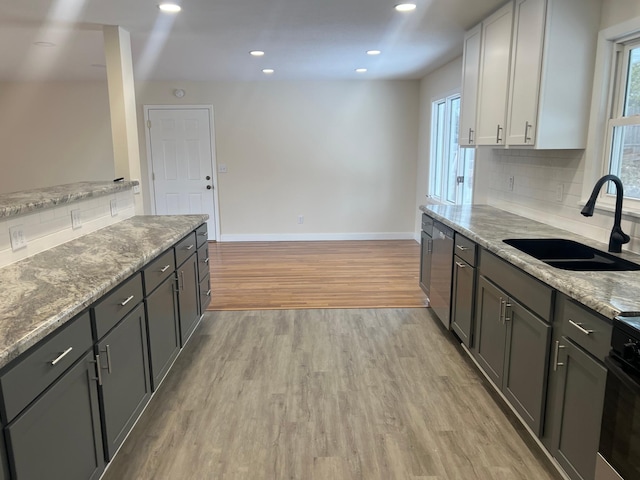 kitchen featuring dishwasher, a sink, a wealth of natural light, and light wood-style floors