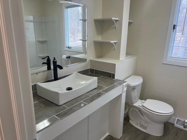 bathroom with toilet, visible vents, a wealth of natural light, and wood finished floors