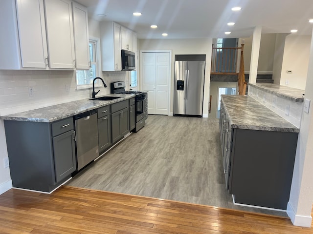 kitchen with tasteful backsplash, recessed lighting, appliances with stainless steel finishes, light wood-style floors, and a sink