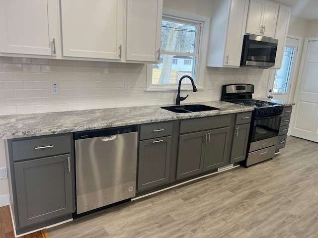 kitchen with light wood-style floors, white cabinetry, stainless steel appliances, and a sink