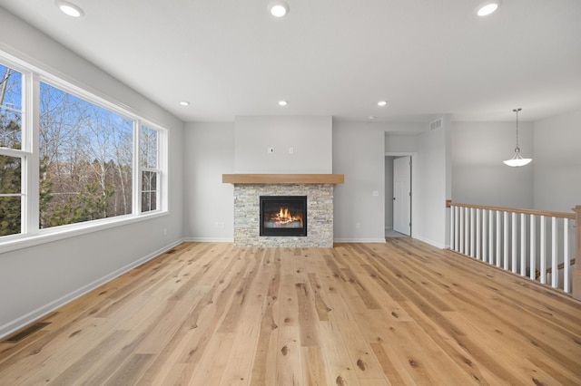 unfurnished living room featuring a healthy amount of sunlight, a fireplace, and light hardwood / wood-style floors