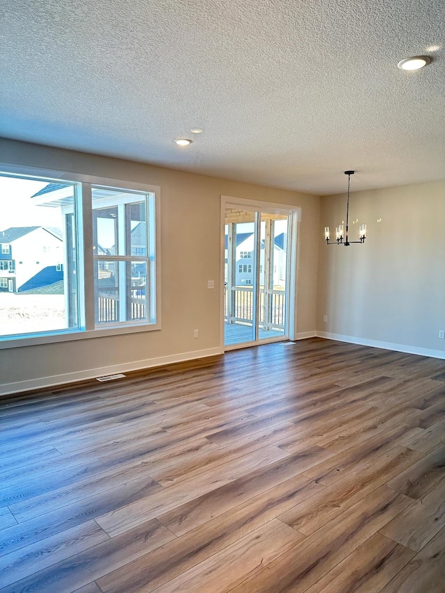 unfurnished room featuring hardwood / wood-style floors, a notable chandelier, and a textured ceiling