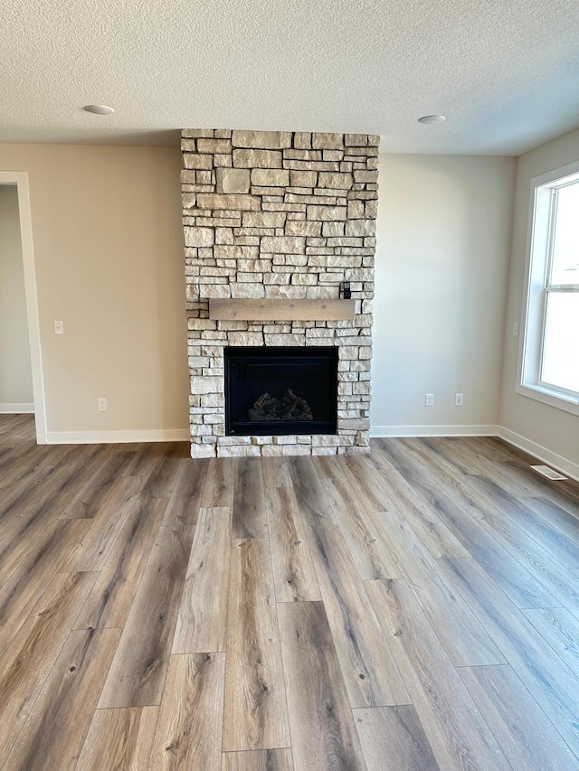 unfurnished living room with hardwood / wood-style floors, a fireplace, and a textured ceiling