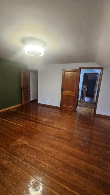 empty room with dark wood-type flooring and vaulted ceiling