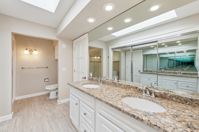 bathroom with a skylight, walk in shower, vanity, hardwood / wood-style floors, and toilet