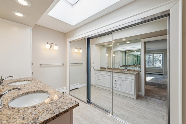 bathroom featuring vanity, a skylight, and a baseboard radiator