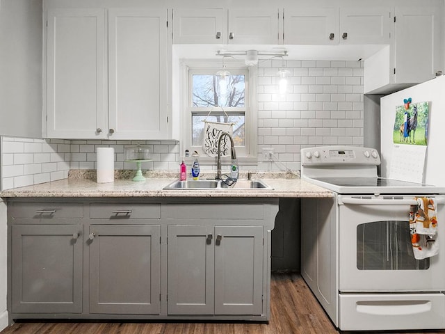 kitchen with white electric range oven, gray cabinets, dark hardwood / wood-style flooring, and sink