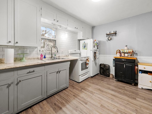 kitchen with sink, backsplash, white appliances, gray cabinets, and light wood-type flooring