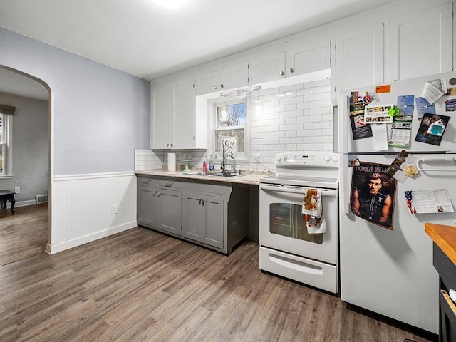 kitchen featuring backsplash, gray cabinetry, white appliances, hardwood / wood-style floors, and white cabinetry