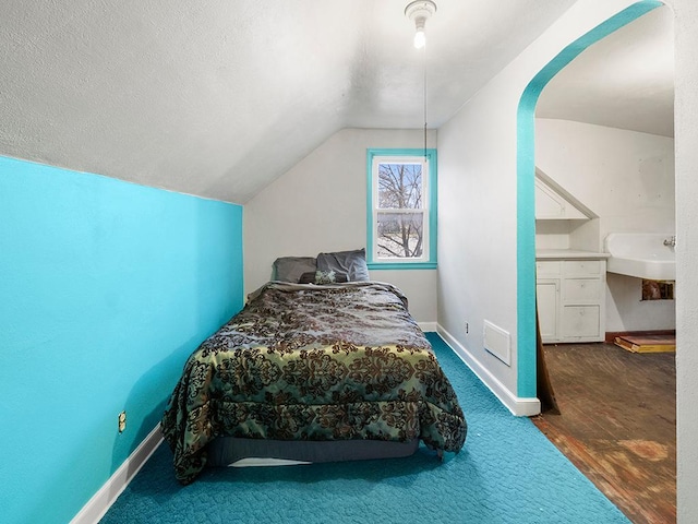 bedroom featuring a textured ceiling, hardwood / wood-style floors, and lofted ceiling