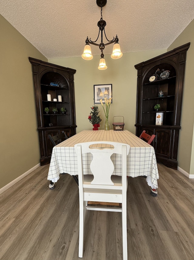 dining room with hardwood / wood-style floors, a textured ceiling, and vaulted ceiling