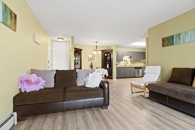 living room with light wood-type flooring, sink, a notable chandelier, and a baseboard heating unit