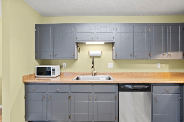 kitchen featuring a textured ceiling, stainless steel dishwasher, sink, and gray cabinetry