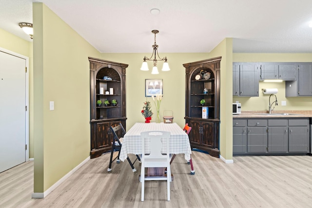 dining space featuring light hardwood / wood-style floors, sink, and a chandelier