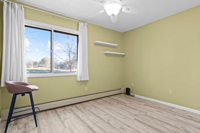 spare room with ceiling fan, a baseboard radiator, light hardwood / wood-style flooring, and a textured ceiling