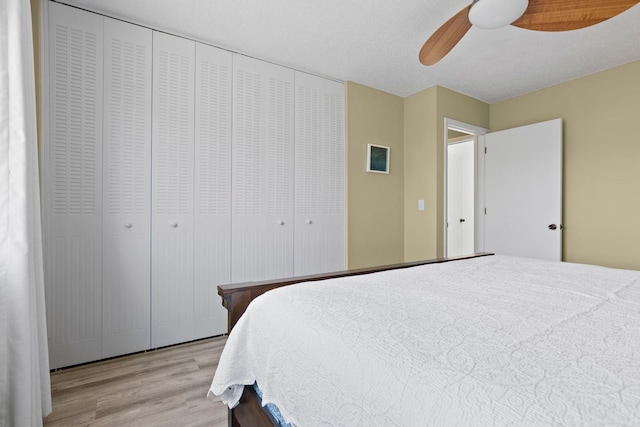 bedroom featuring a closet, a textured ceiling, ceiling fan, and light hardwood / wood-style flooring