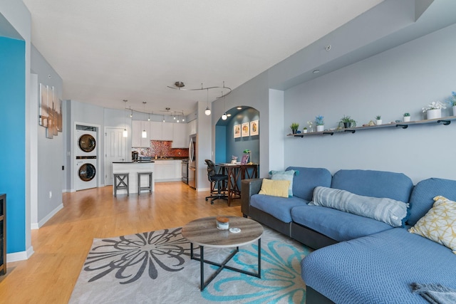 living room featuring stacked washer / dryer and light hardwood / wood-style flooring