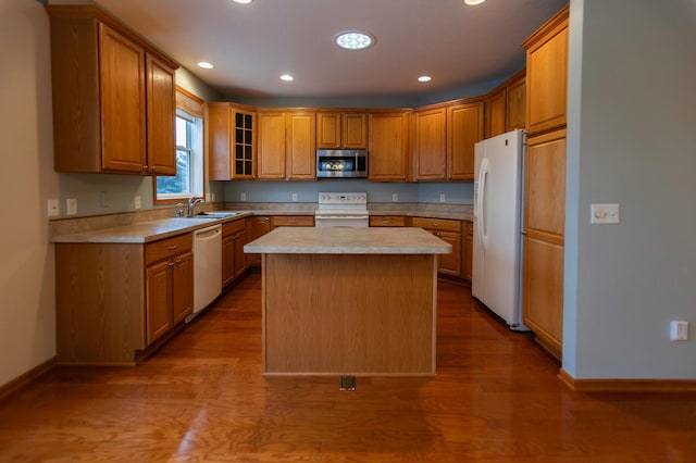 kitchen with white appliances, a center island, hardwood / wood-style flooring, and sink