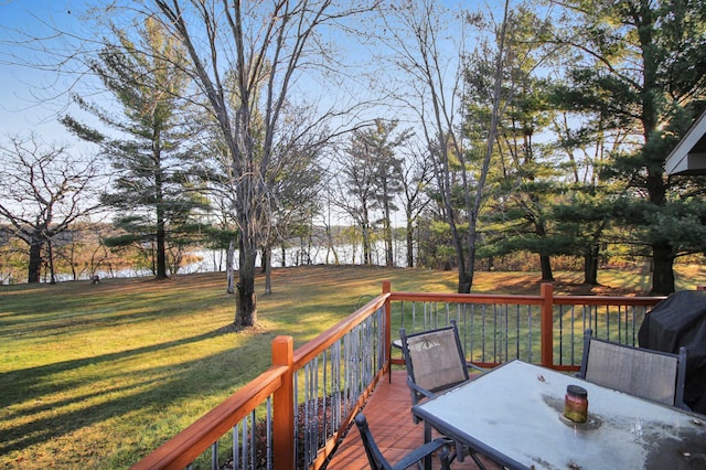 wooden deck featuring outdoor dining area and a lawn