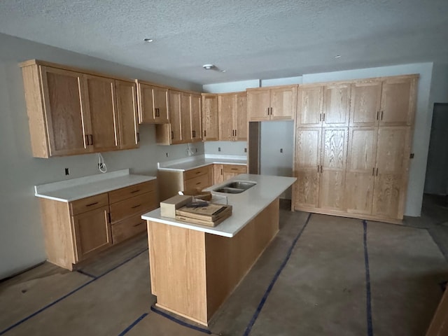 kitchen featuring a textured ceiling, sink, and a kitchen island with sink