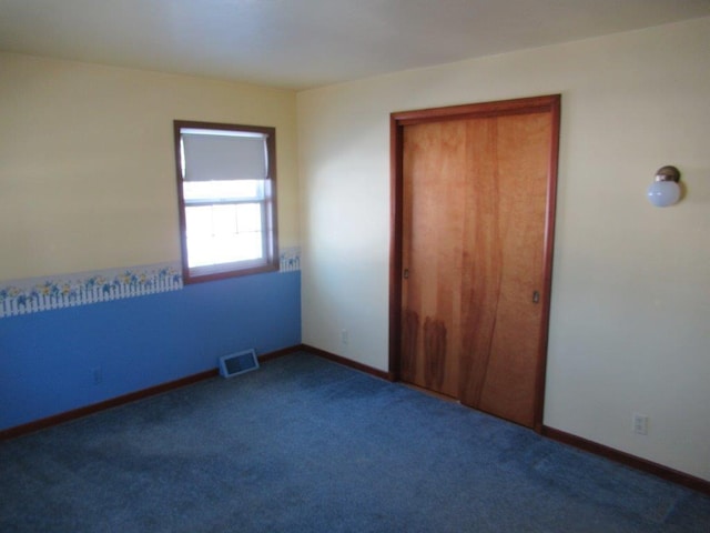 unfurnished bedroom with dark carpet and a closet