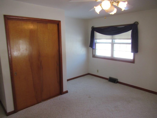 unfurnished bedroom featuring ceiling fan, light carpet, and a closet