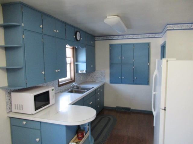 kitchen with blue cabinetry, sink, dark wood-type flooring, and white appliances