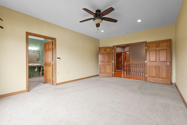 unfurnished bedroom featuring ensuite bathroom, ceiling fan, and light colored carpet