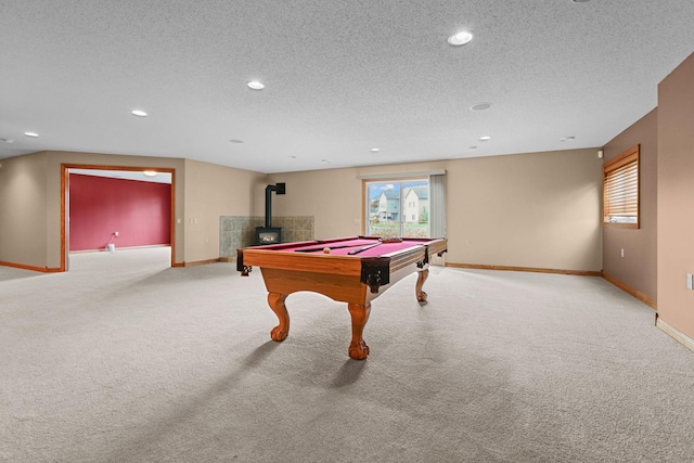 game room with a textured ceiling, a wood stove, light carpet, and pool table