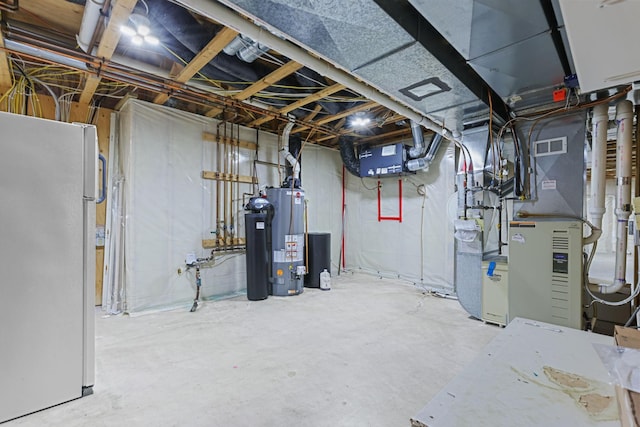 basement featuring water heater and white refrigerator