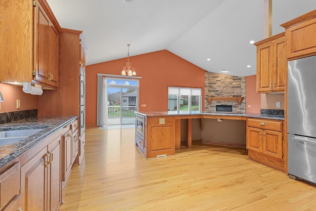 kitchen with sink, pendant lighting, lofted ceiling, appliances with stainless steel finishes, and light wood-type flooring