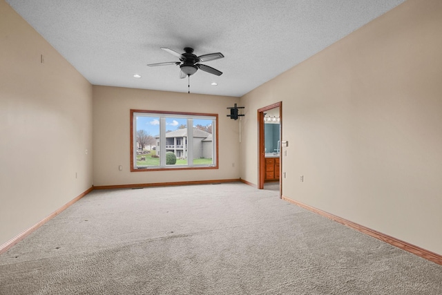 spare room with ceiling fan, light colored carpet, and a textured ceiling