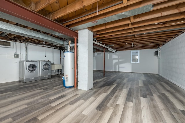 basement with water heater, hardwood / wood-style floors, sink, and independent washer and dryer