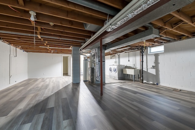 basement featuring hardwood / wood-style flooring, water heater, washer and clothes dryer, and sink