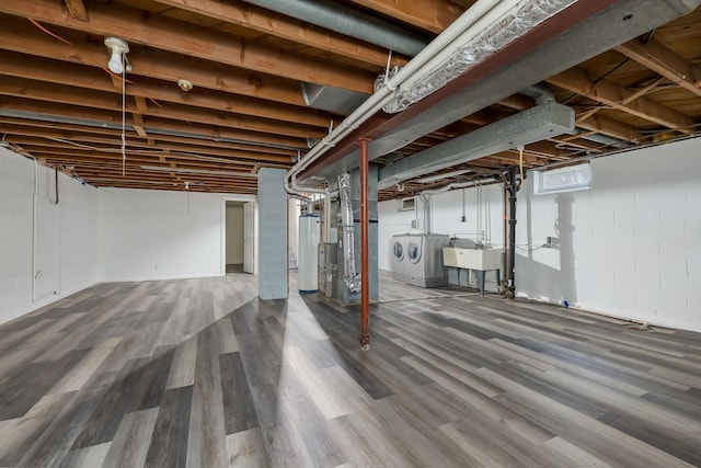 basement featuring water heater, dark hardwood / wood-style flooring, sink, and washing machine and clothes dryer