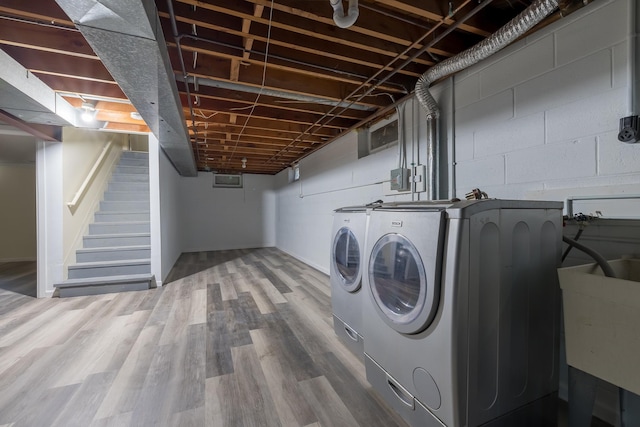 laundry room featuring washer and dryer, wood-type flooring, and sink