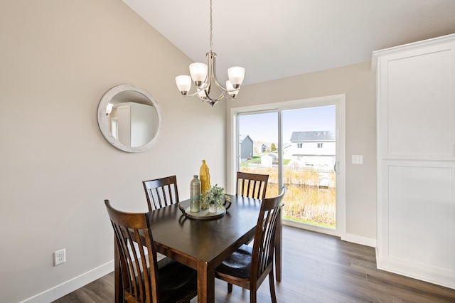 dining space with dark wood-type flooring, lofted ceiling, and a notable chandelier