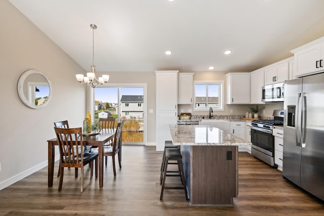 kitchen featuring a kitchen island, white cabinetry, appliances with stainless steel finishes, pendant lighting, and dark wood-type flooring