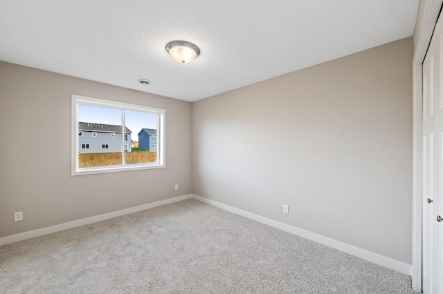 spare room featuring carpet and a textured ceiling