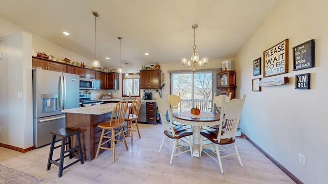 dining room with light hardwood / wood-style floors, a chandelier, sink, and vaulted ceiling